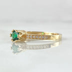 Gold ring with a green gemstone and small diamonds on a light gray background