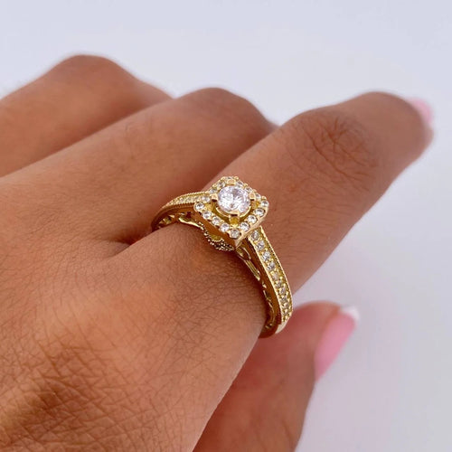 Gold ring with a diamond on a finger against a white background