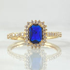 Gold ring with a blue gemstone on a light gray background