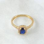 Gold ring with a blue gemstone on a white background