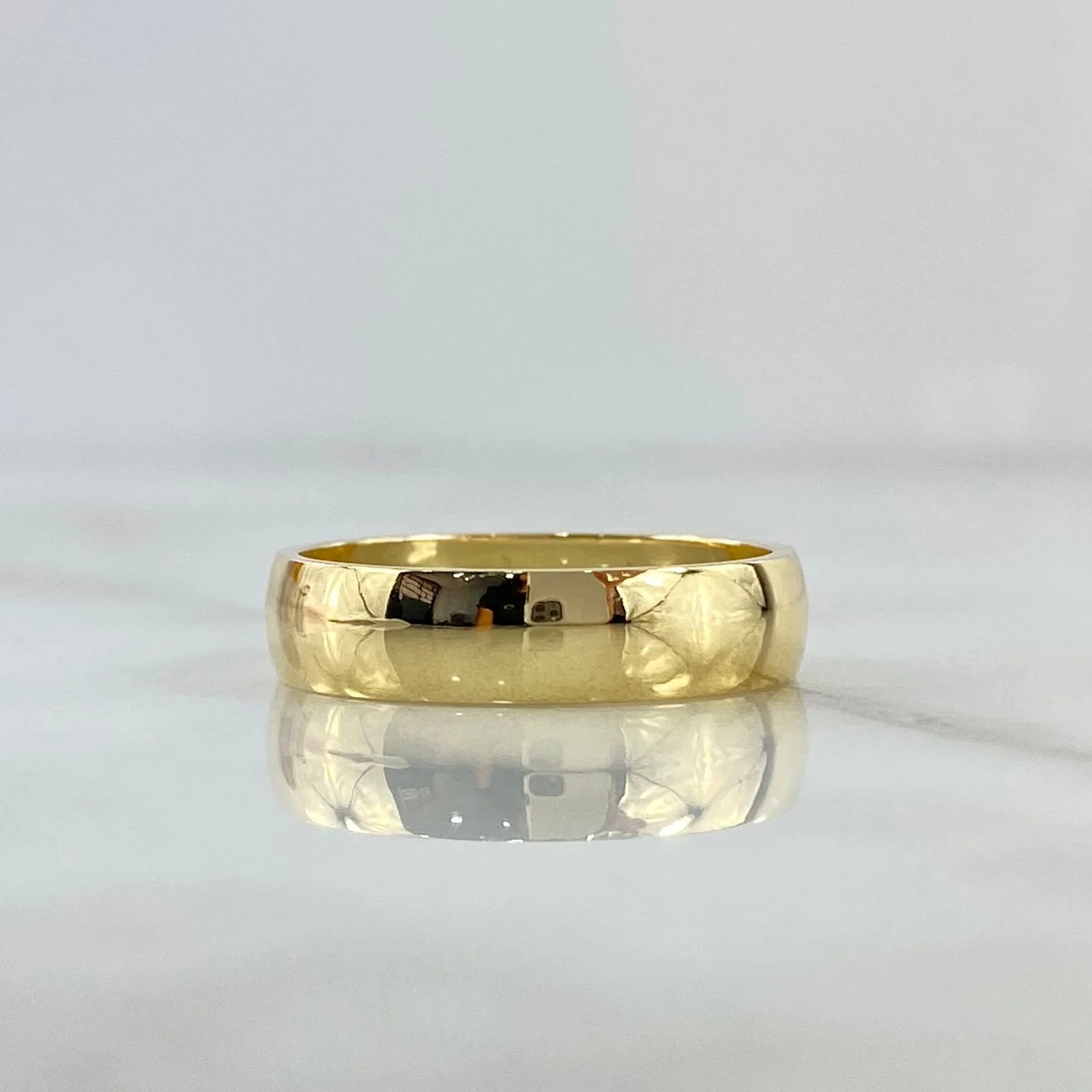Gold ring on a reflective surface with a light gray background