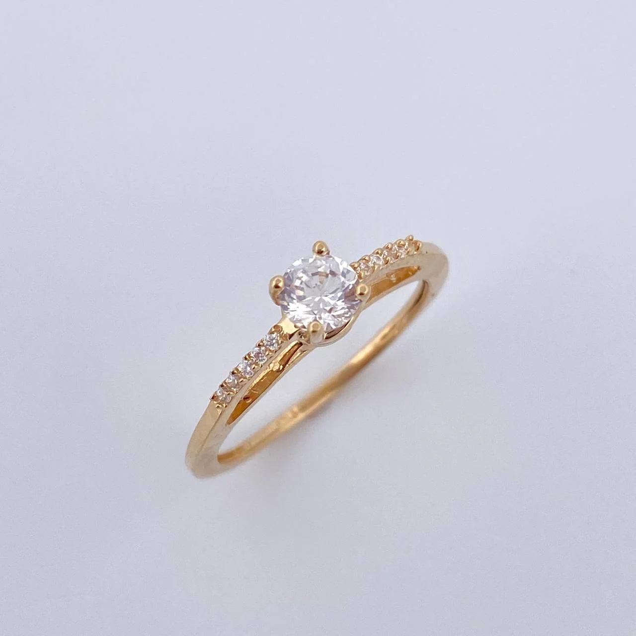Gold ring with a diamond on a light gray background