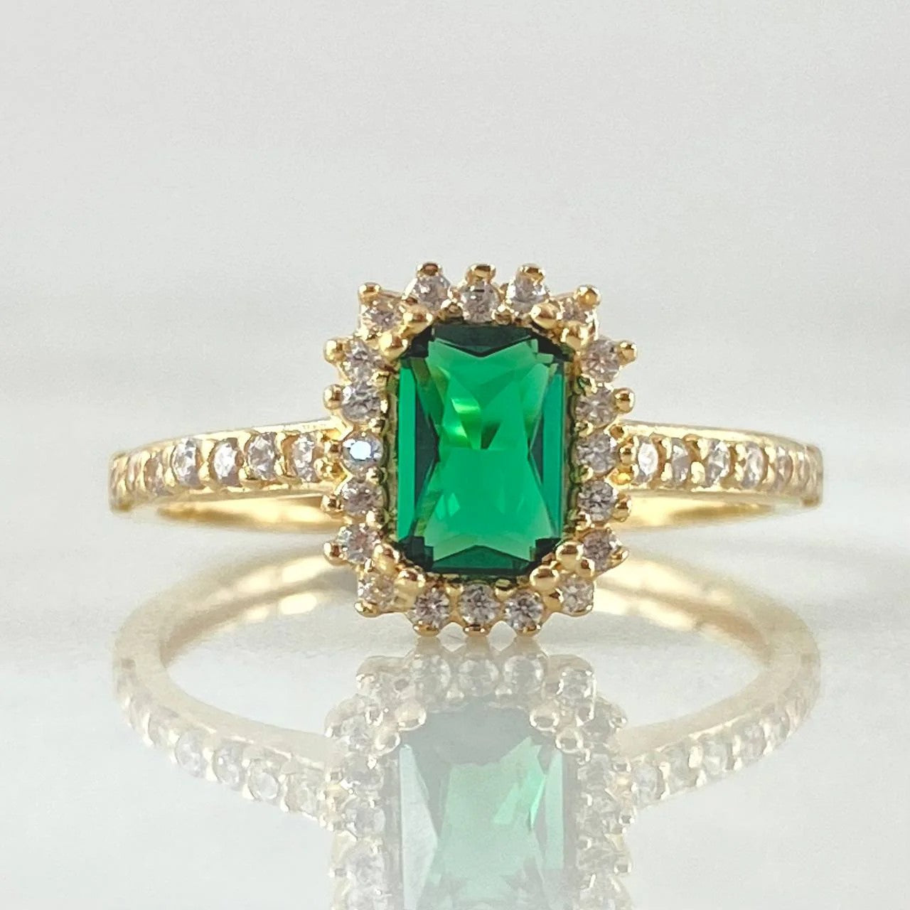 Gold ring with a green gemstone on a white background