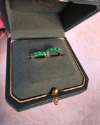 Green gemstone ring in a jewelry box on a pink textured background