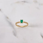 Gold ring with a green gemstone on a marble background