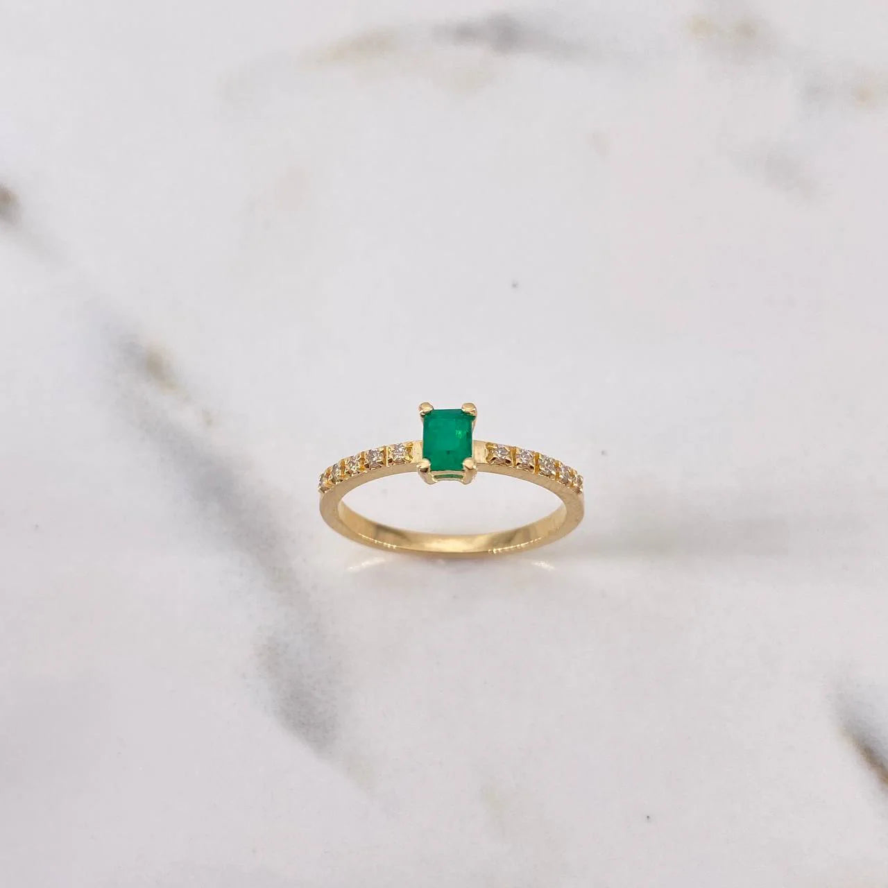 Gold ring with a green gemstone on a marble background