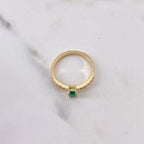 Gold ring with a green gemstone on a marble surface