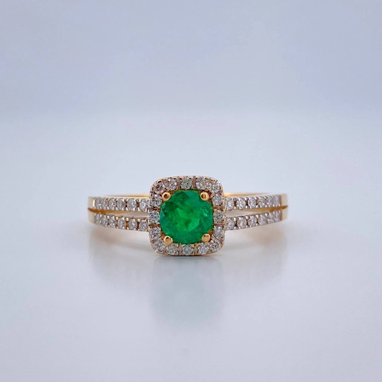 Ring with a green gemstone and diamond accents on a light gray background