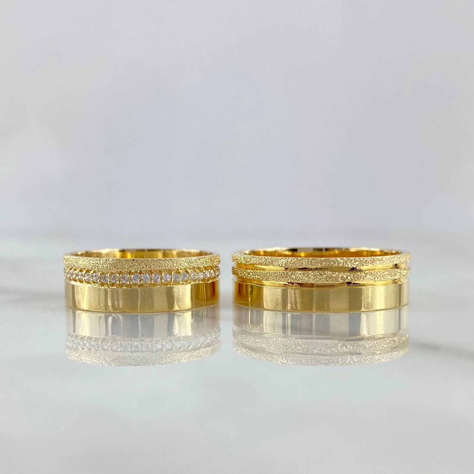 Two gold rings with diamond accents on a light gray background
