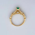 Gold ring with a green gemstone on a light gray background