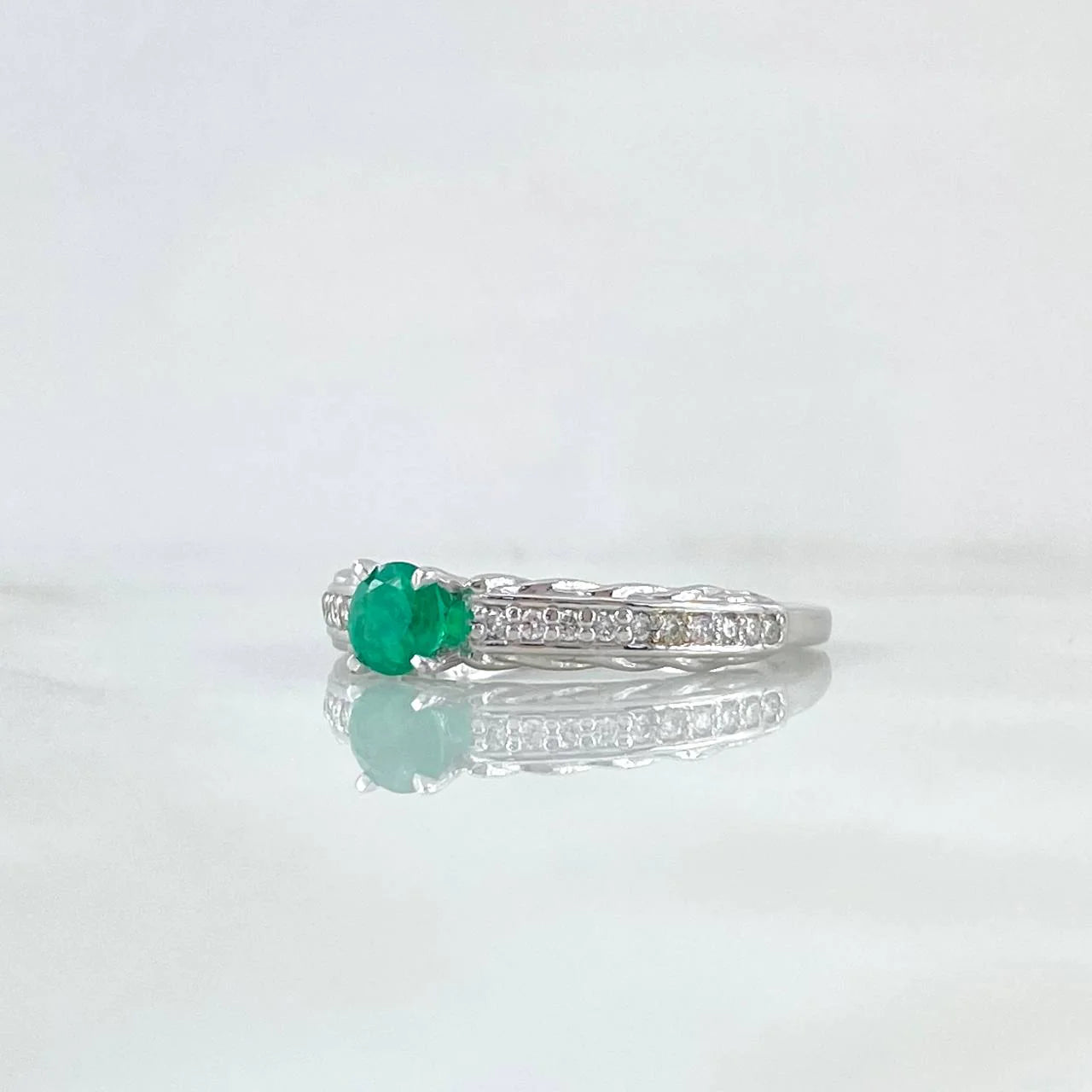 White gold ring with a green gemstone on a white background