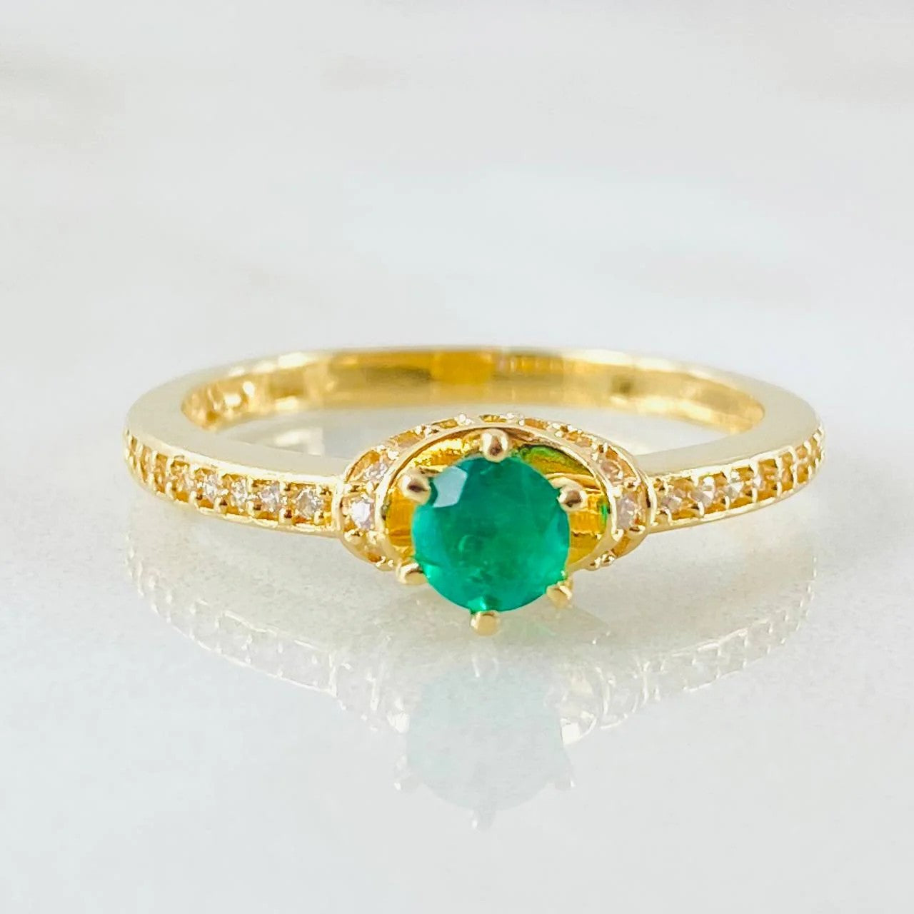 Gold ring with a green gemstone on a white background