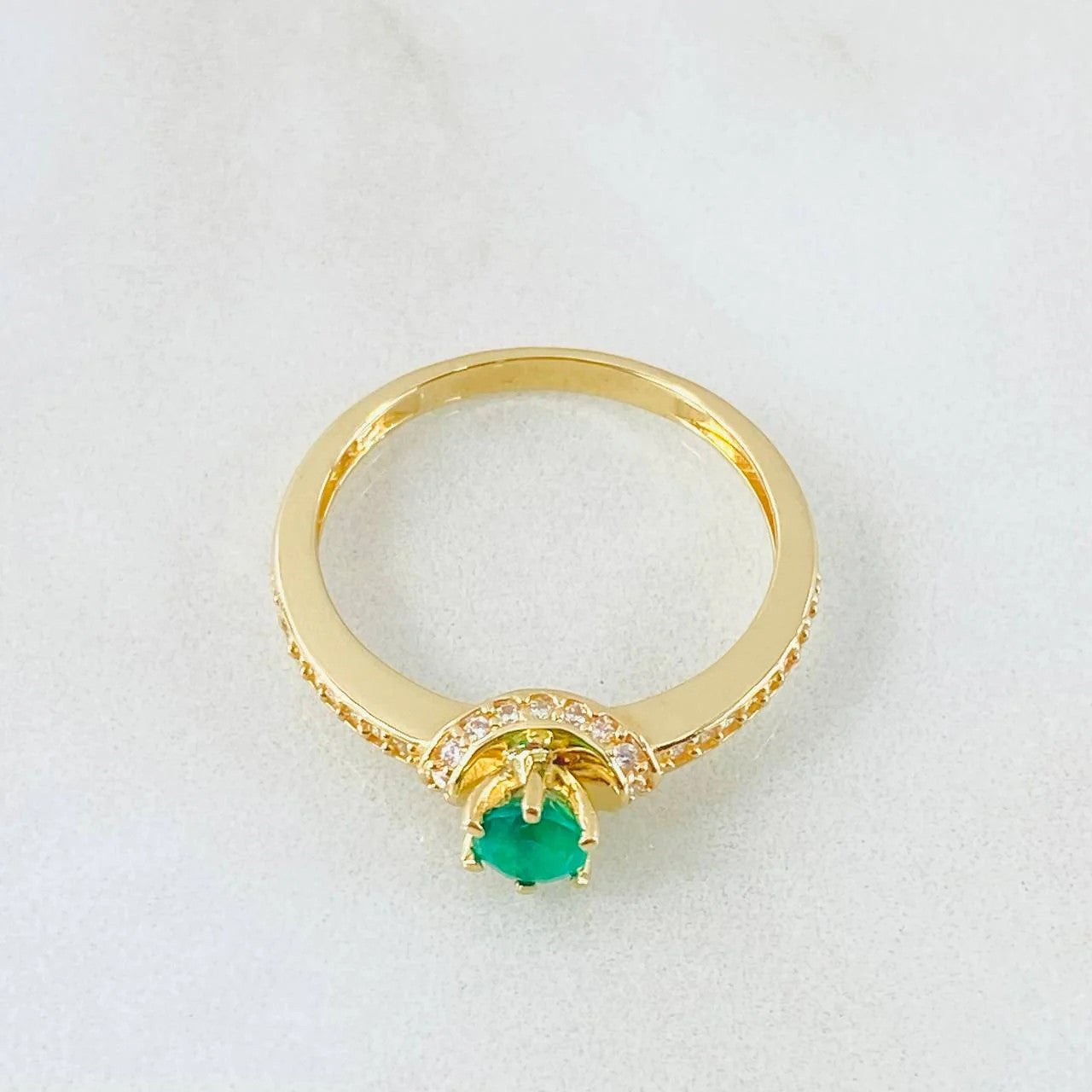 Gold ring with a green gemstone on a white background