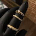 Three gold and diamond rings on a black glove with a blurred background