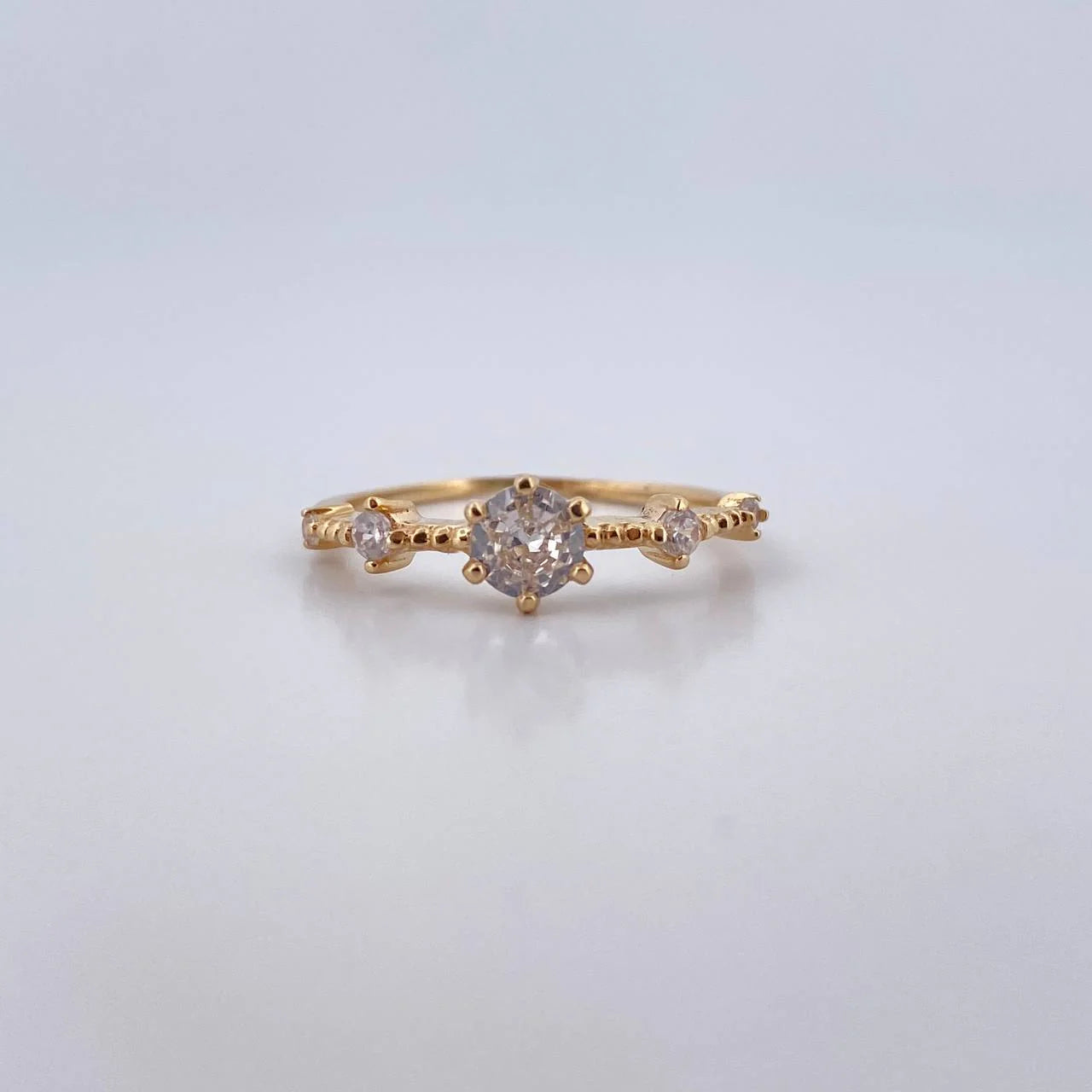 Gold ring with diamonds on a light gray background