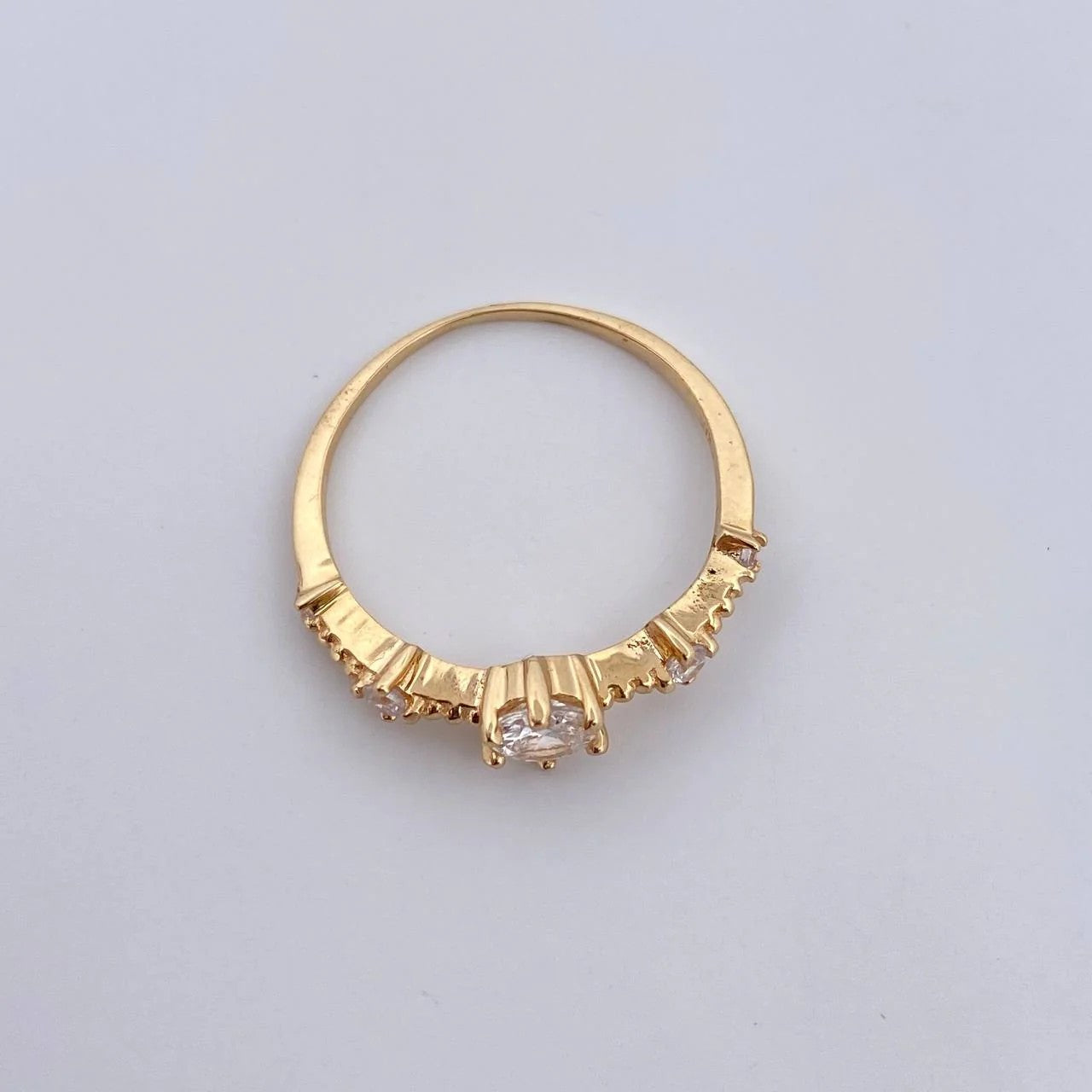 Gold ring with a central gemstone on a light gray background