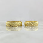 Two gold rings with a textured pattern on a light gray background