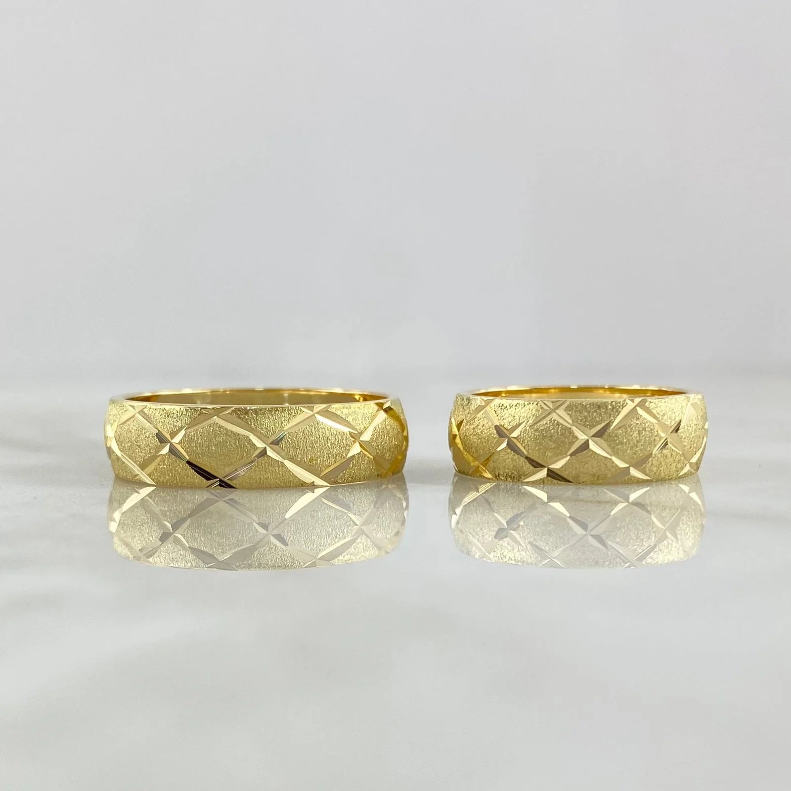 Two gold rings with a textured pattern on a light gray background