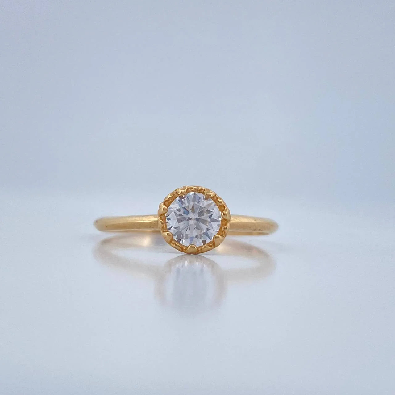 Gold ring with a diamond on a light blue background