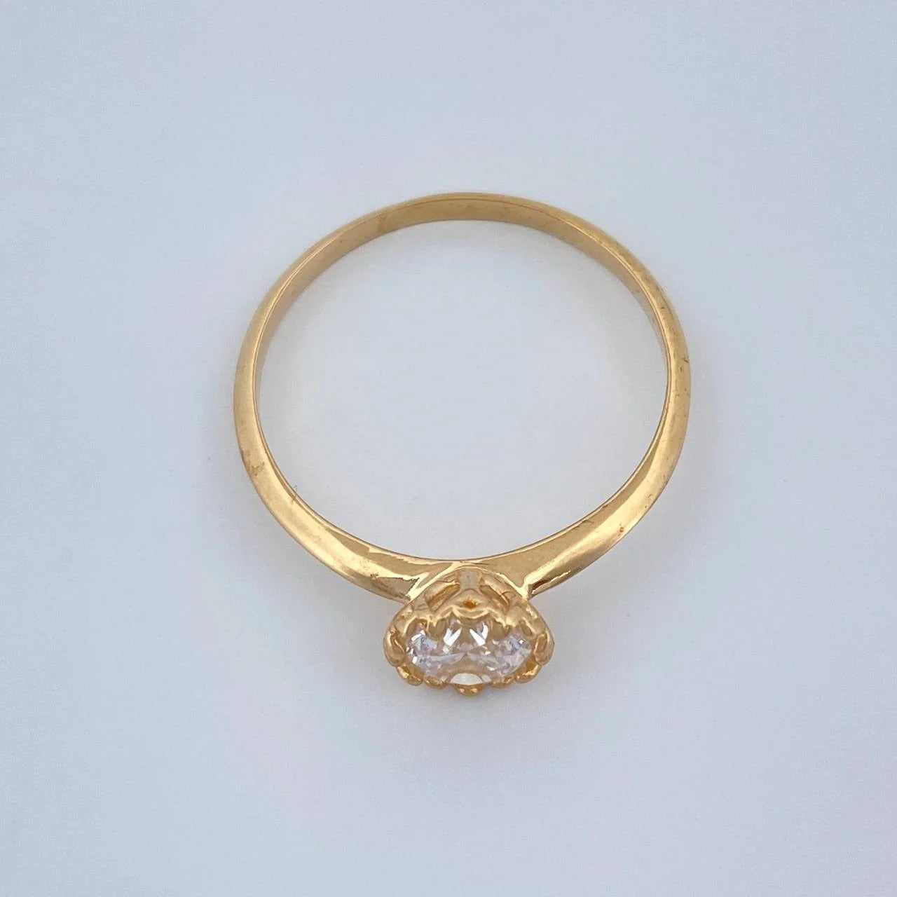 Gold ring with a diamond on a light gray background