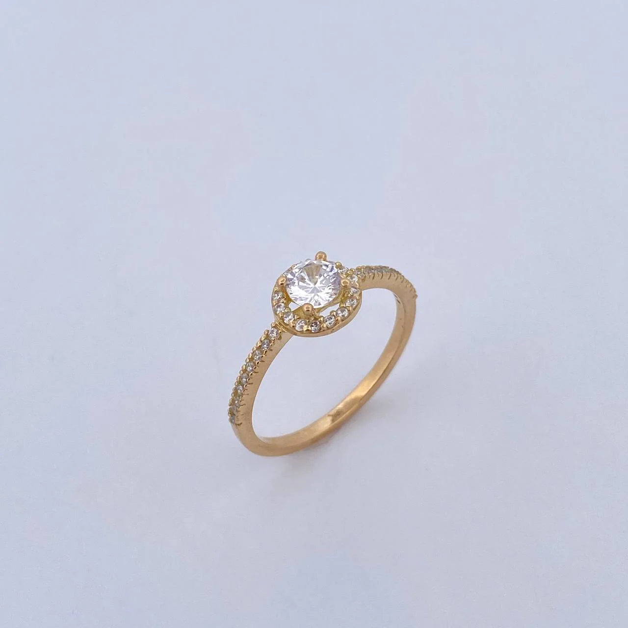 Gold ring with a diamond on a light gray background