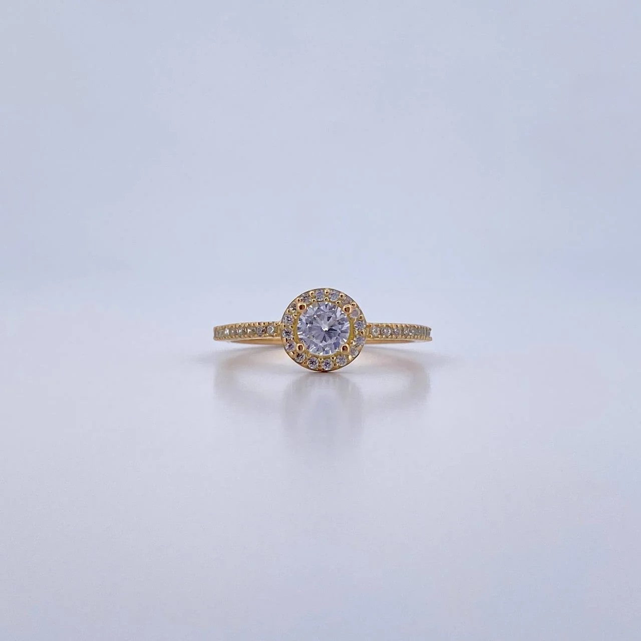 Gold ring with a diamond on a light gray background