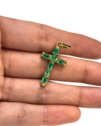 close-up of emerald cut Colombian emeralds set in 18K gold cross pendant, held in hand | Gado Jewellers, fine Canadian jewellery