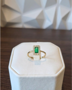 emerald cut Colombian emerald ring with diamond halo in 18K gold on display stand | Gado Jewellers, fine Canadian jewellery
