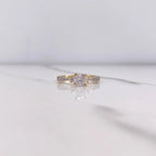 Gold ring with a diamond on a white marble surface