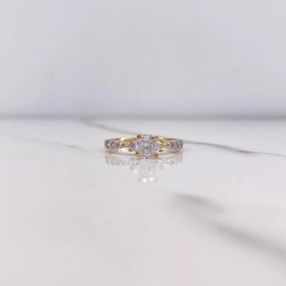 Gold ring with a diamond on a white marble surface