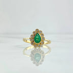 Gold ring with a green gemstone on a light gray background