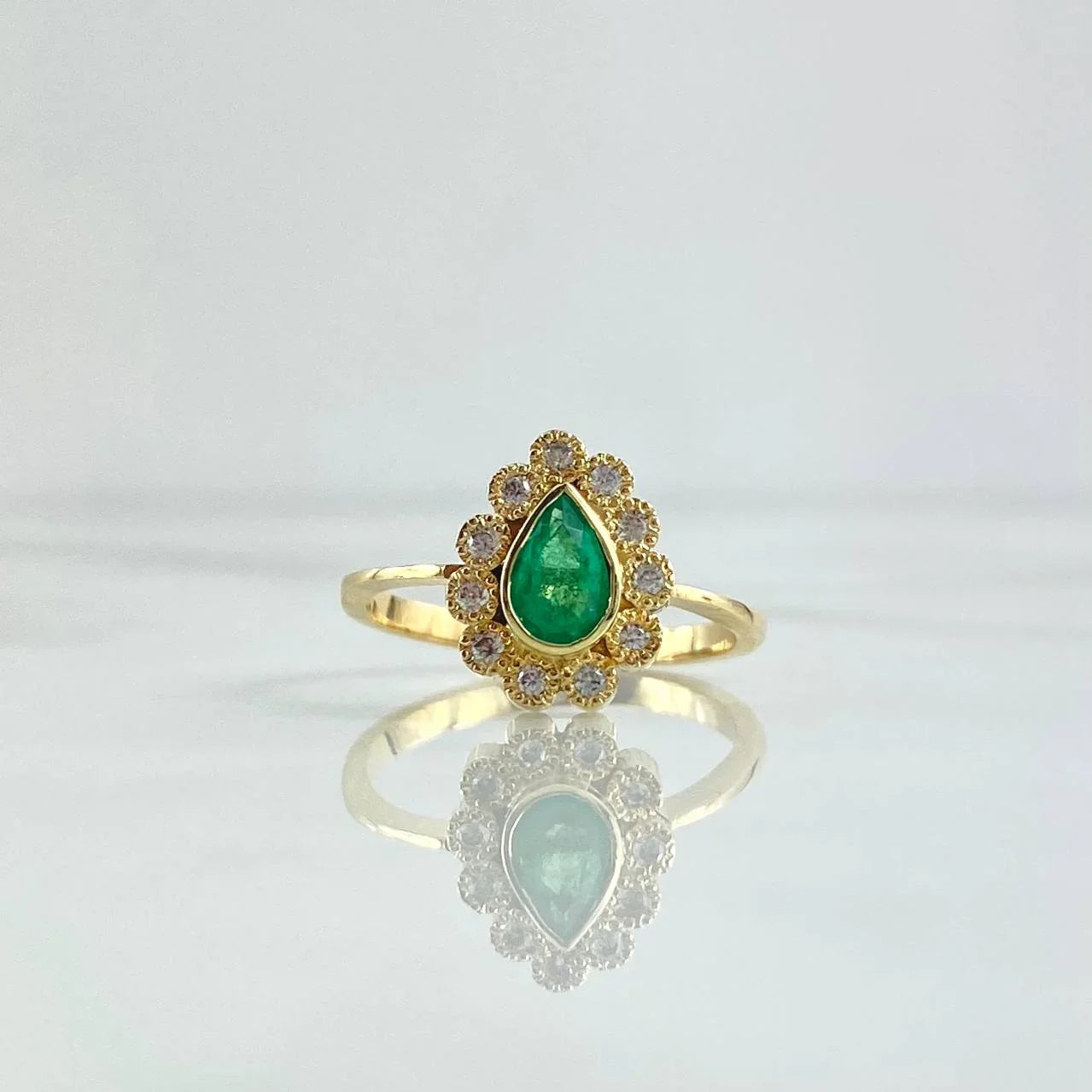 Gold ring with a green gemstone on a light gray background