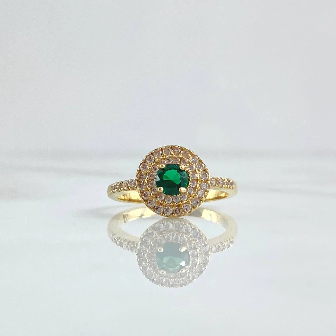 Gold ring with a green gemstone on a light gray background