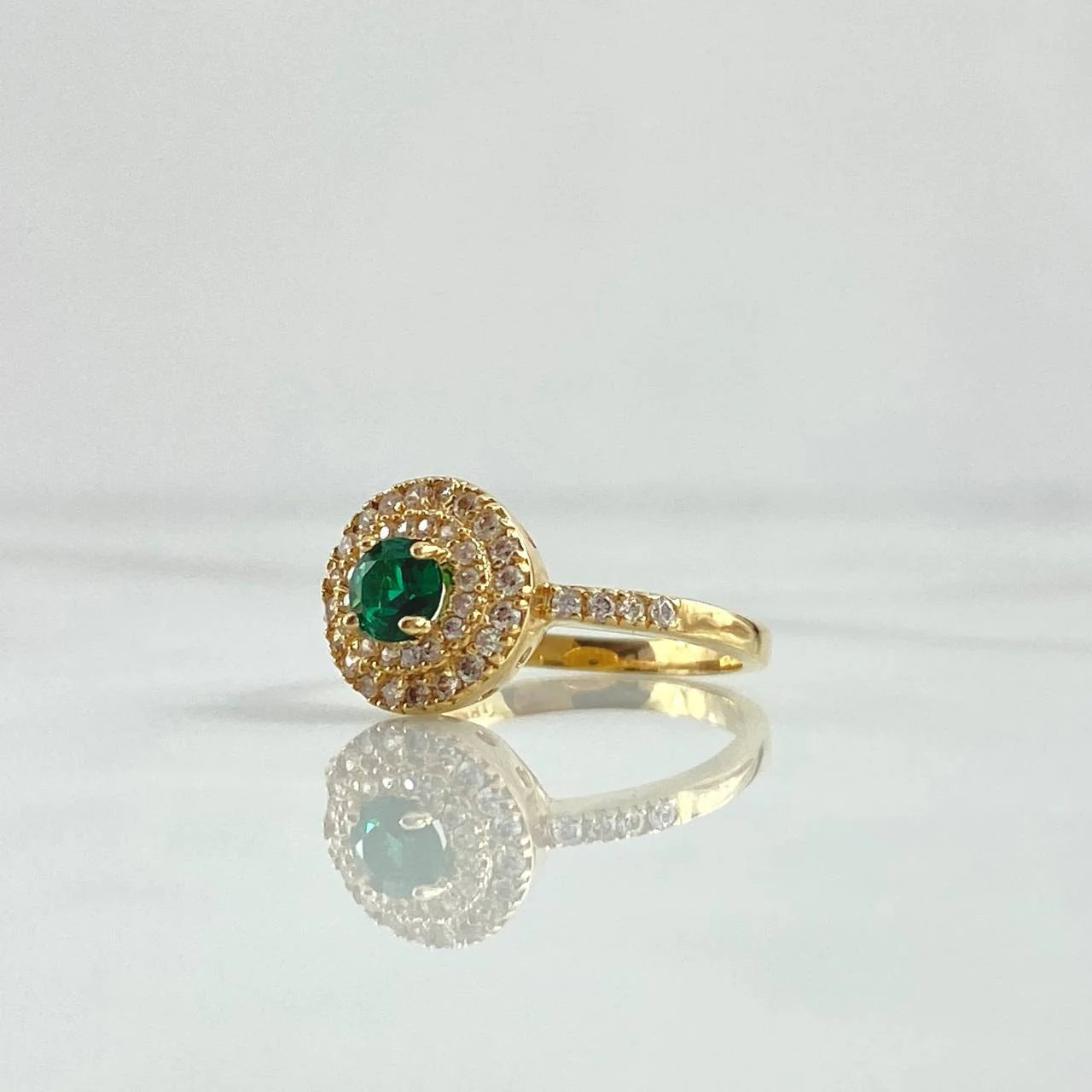 Gold ring with a green gemstone on a light gray background