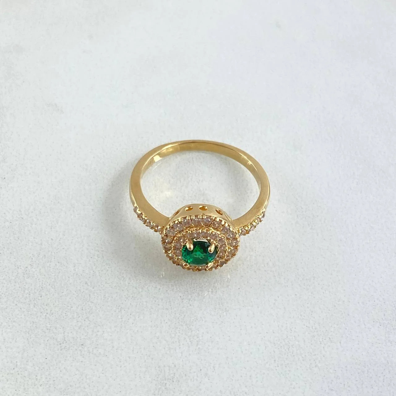 Gold ring with a green gemstone on a white background