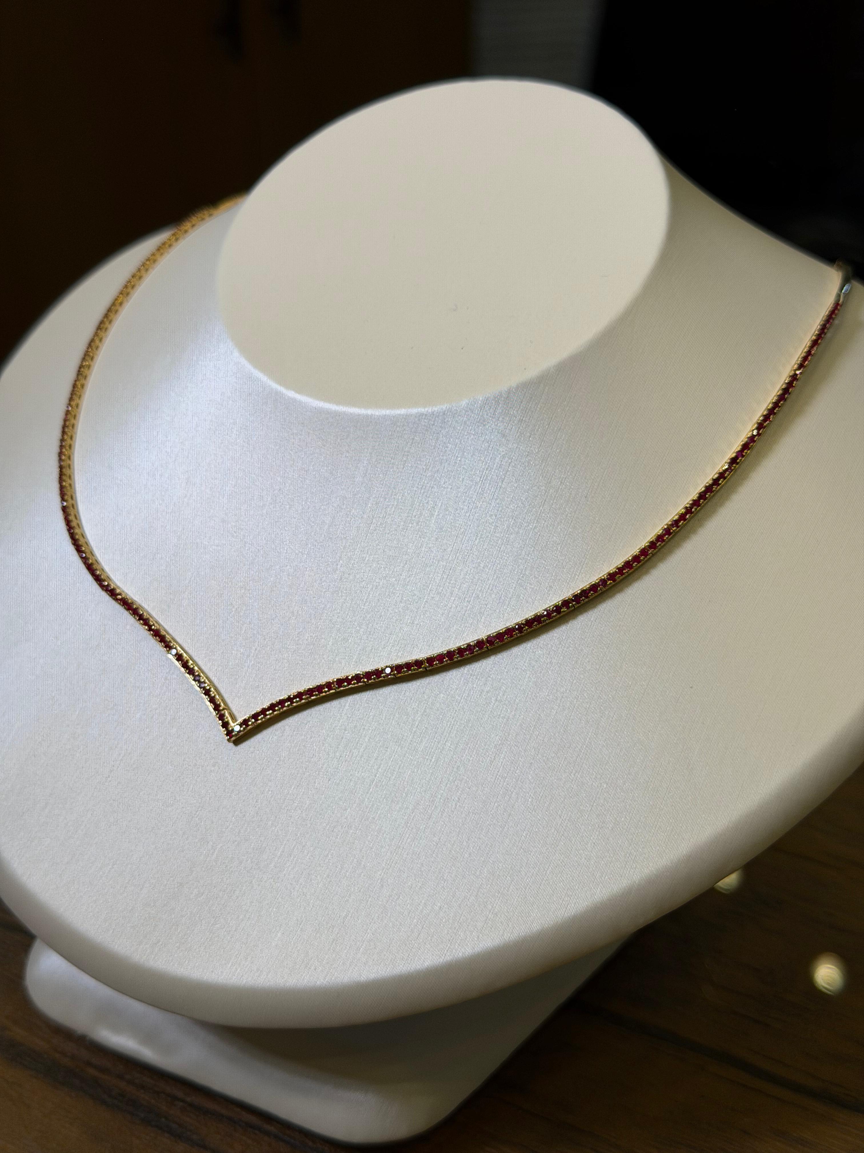 Gold necklace on a white stand with a dark background