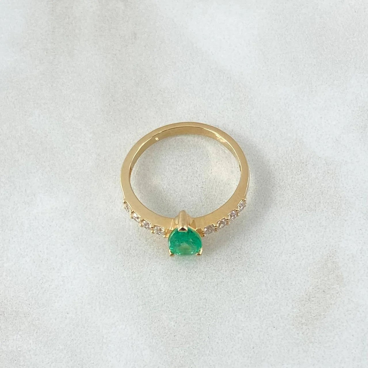 Gold ring with a green gemstone on a white background
