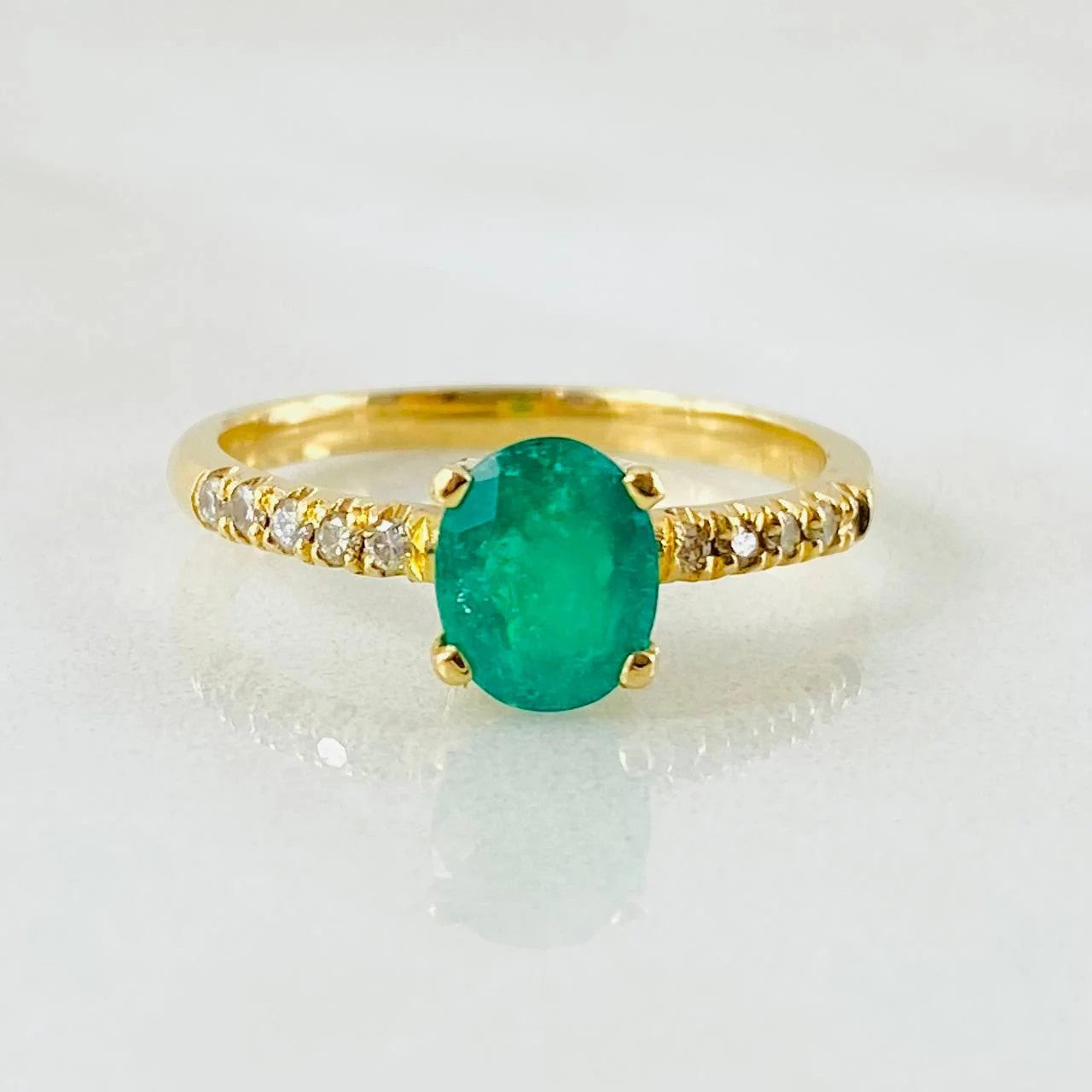 Gold ring with a green gemstone on a white background