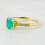 Gold ring with a green gemstone on a light gray background