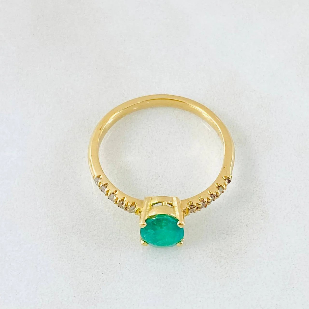 Gold ring with a green gemstone on a white background