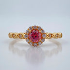 Gold ring with a pink gemstone on a light gray background