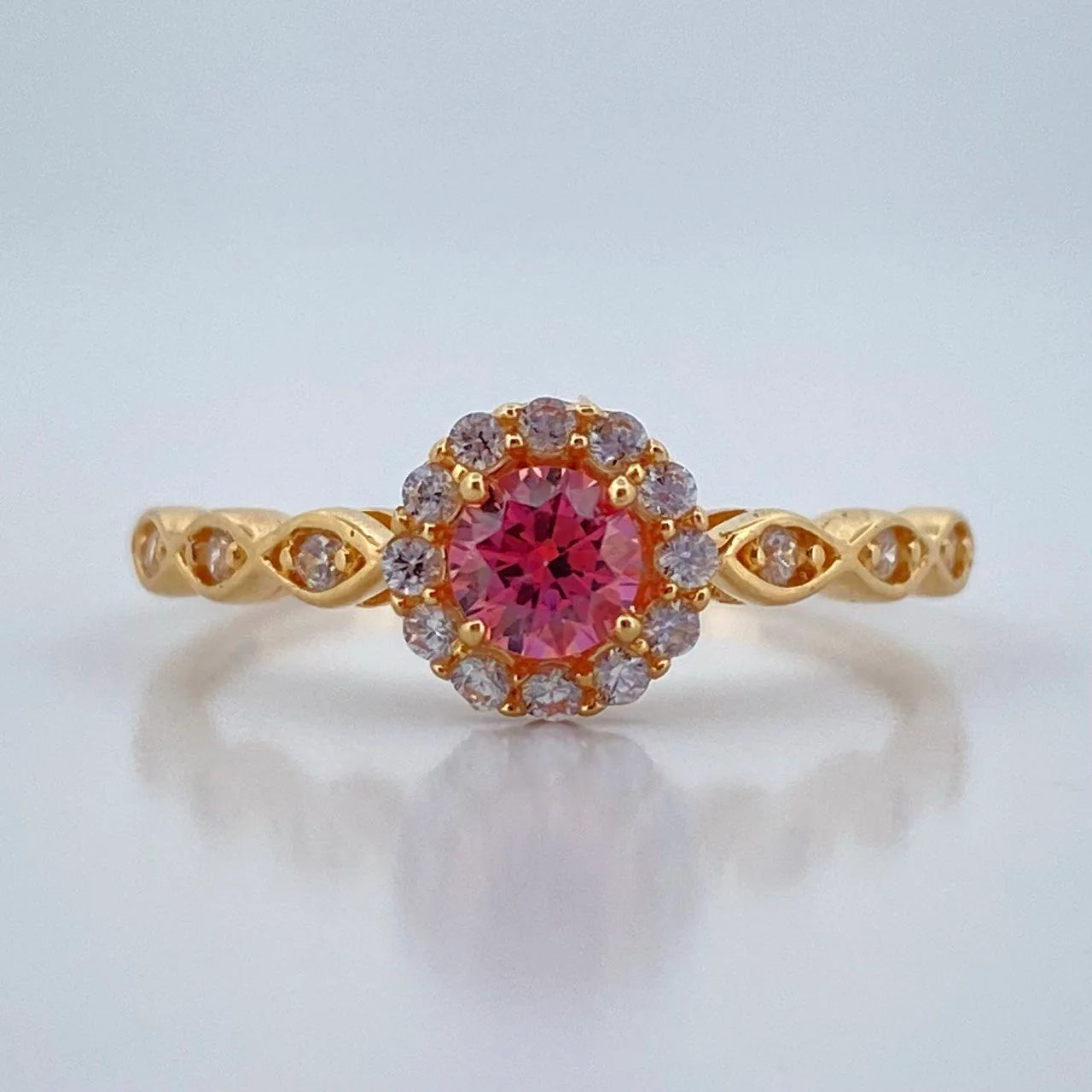 Gold ring with a pink gemstone on a light gray background