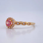 Gold ring with a pink gemstone on a light gray background