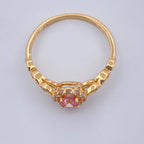 Gold ring with a pink gemstone on a light gray background