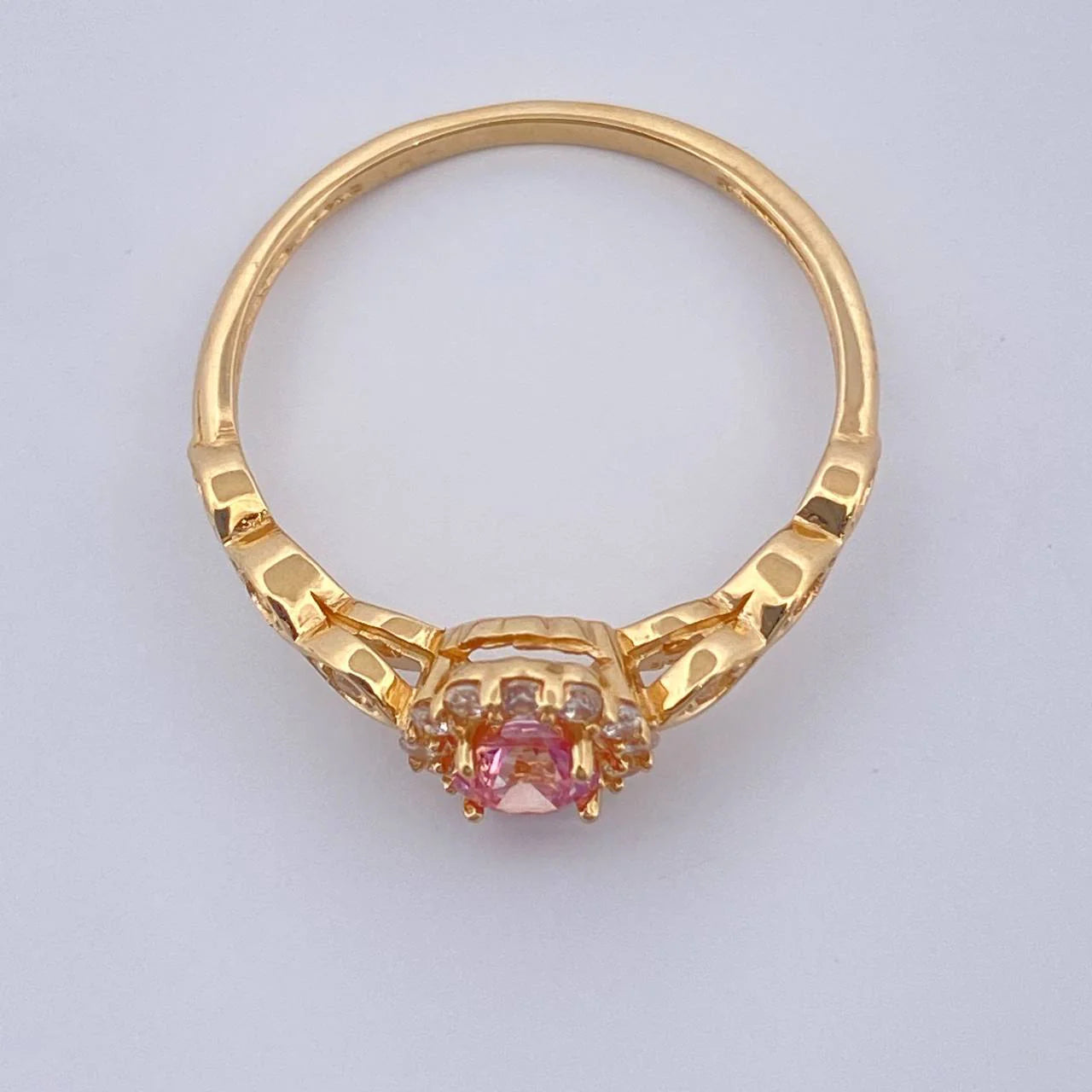 Gold ring with a pink gemstone on a light gray background