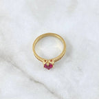 Gold ring with a red gemstone on a white fabric background