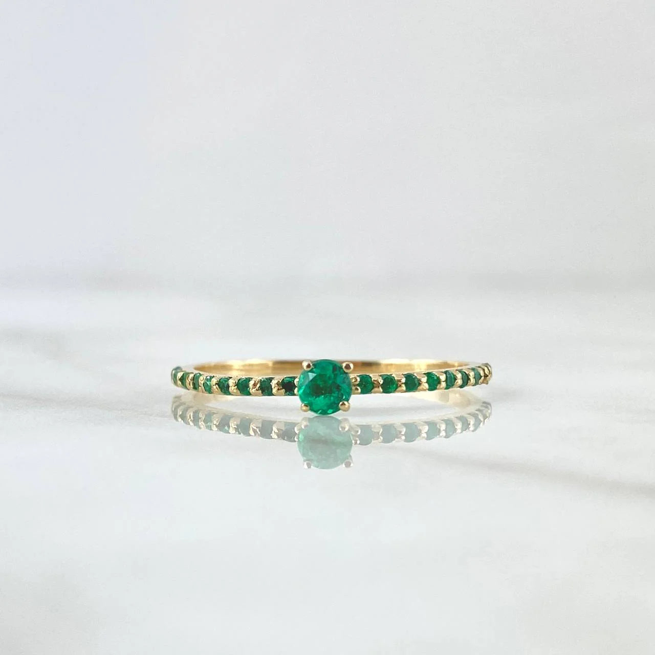 Gold ring with green gemstone on a white background