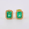 Pair of emerald green gemstone earrings with gold and diamond accents on a white background