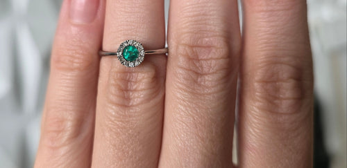 Colombian emerald diamond halo ring worn on hand, 18K white gold, Gado Jewellers