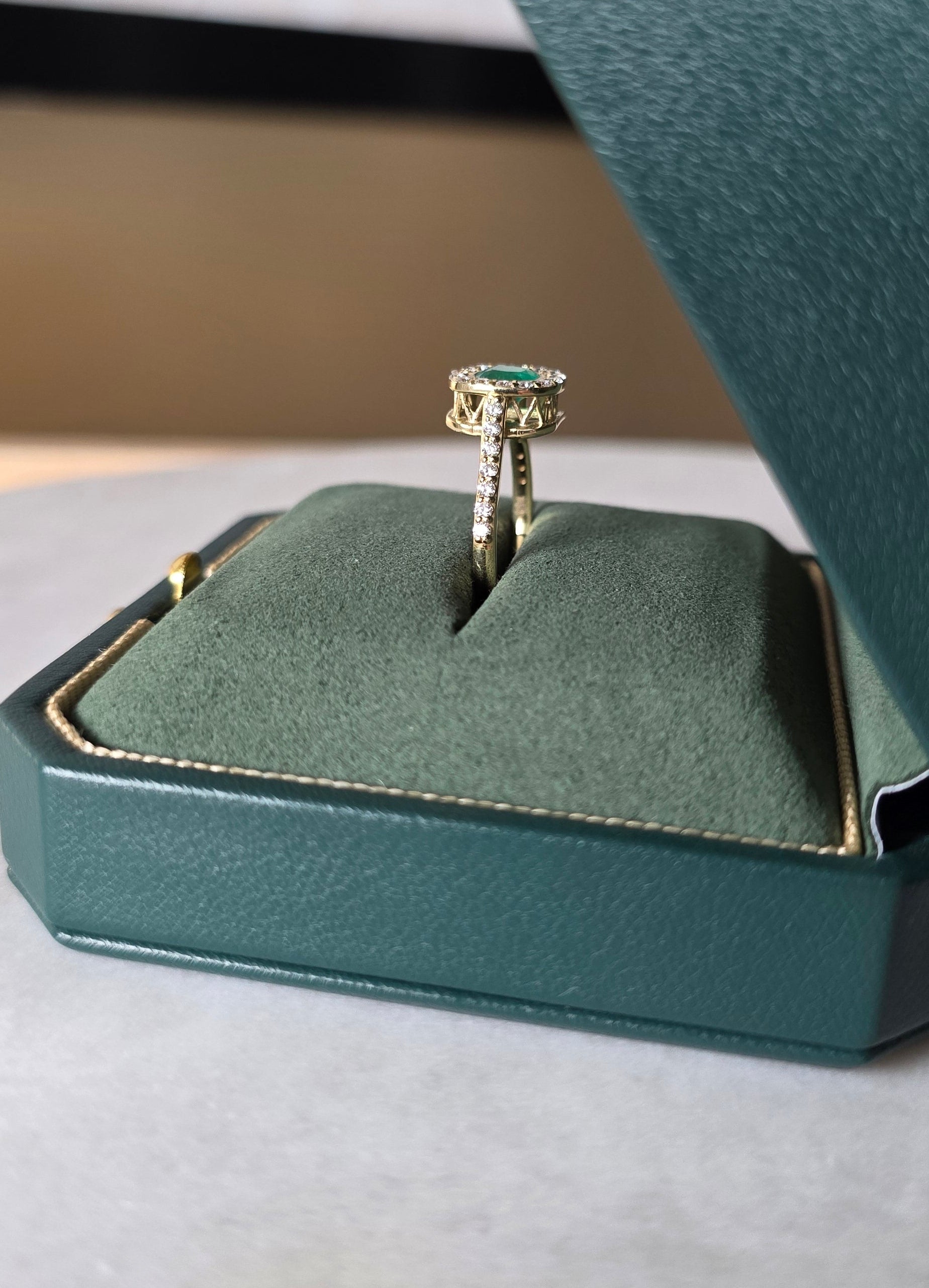 cushion cut natural colombian emerald center stone, natural diamond halo, engagement ring in 18K yellow gold, studio shot in signature Gado packaging, fully certified gemstones and gold purity | Gado Jewellers Toronto Fine Jewelry Custom Engagement Rings